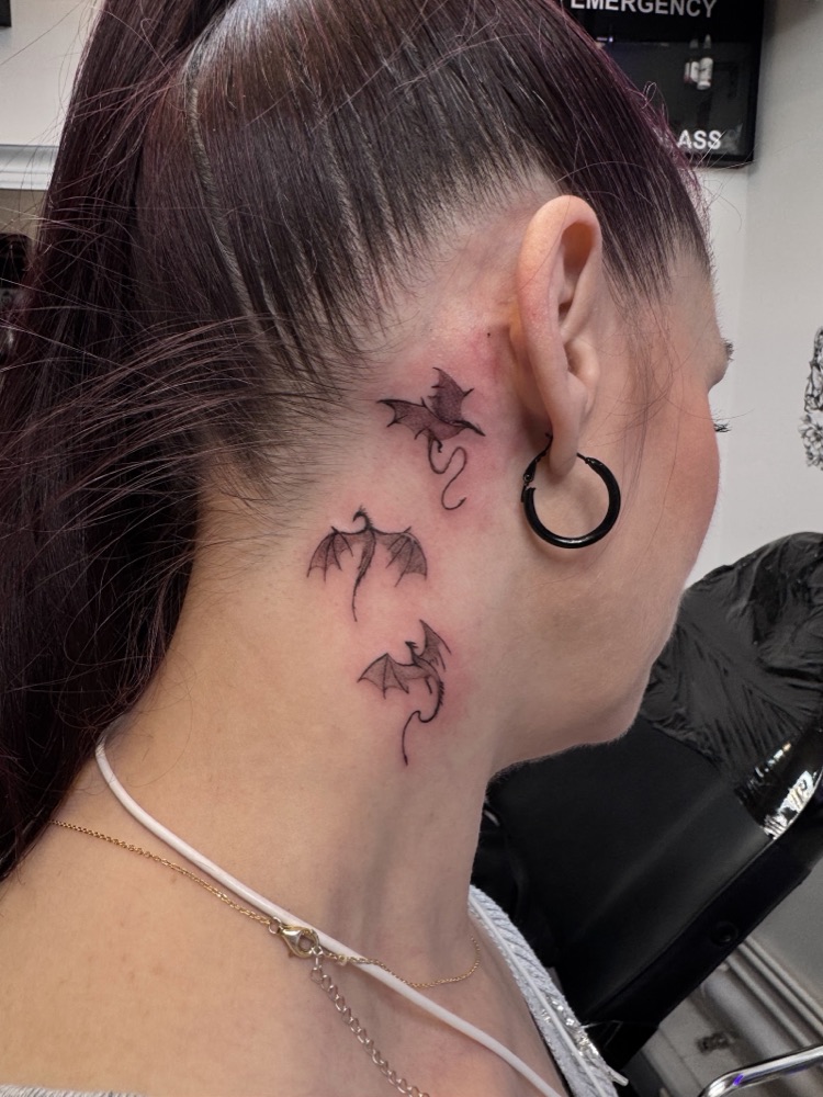 Fine-line dragons tattooed behind the ear and down the neck