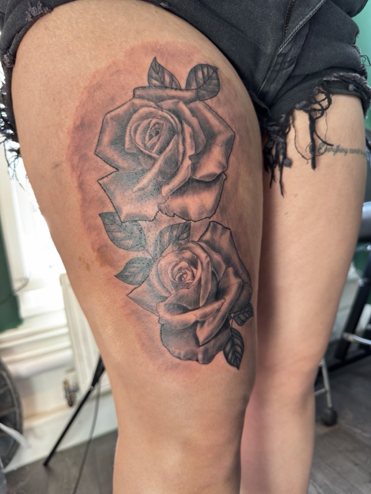 Black and grey realism rose tattoo on a thigh