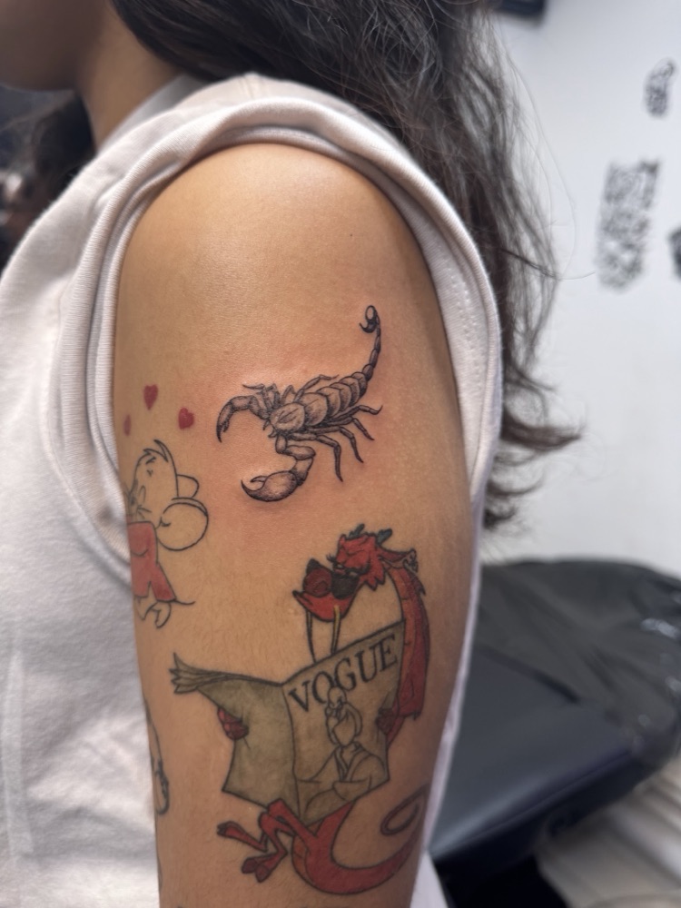 Detailed scorpion tattoo on an upper arm alongside colour pieces